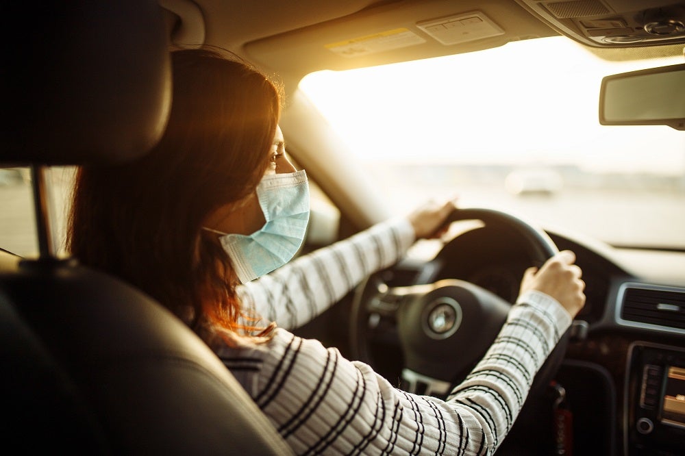 Women driving with a mask on to receive urgent care services