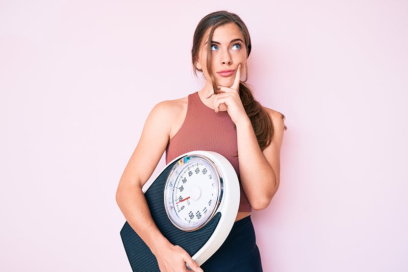 woman holding scale and thinking