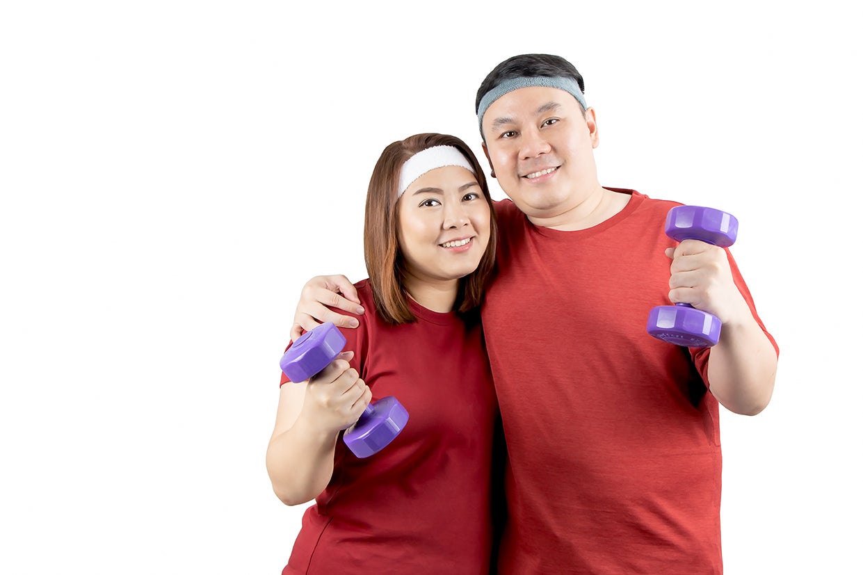 "Exercising couple holding weights wearing red"