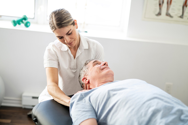 provider helping male patient with vestibular therapy