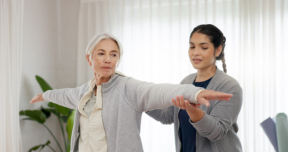 Provider helping a woman balance and hold her arm out.