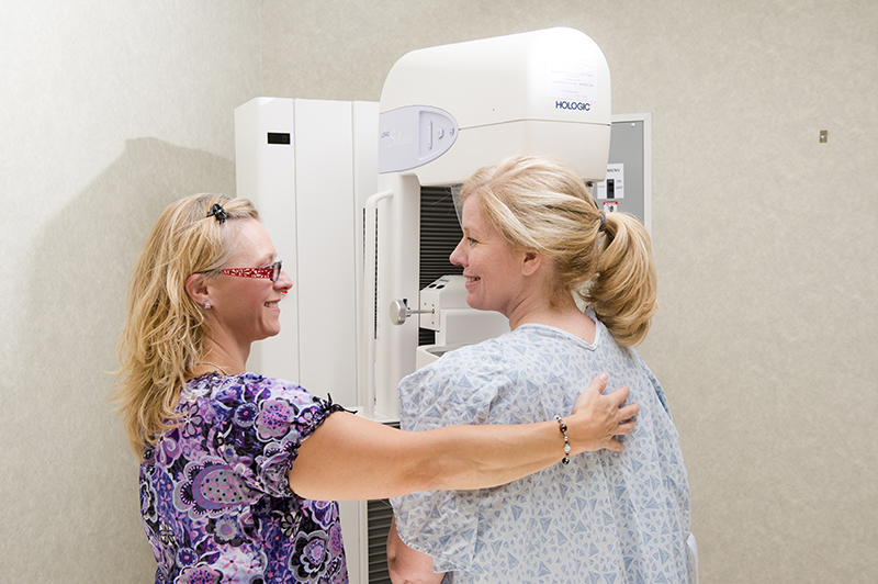 a provider giving a smiling woman a mammogram